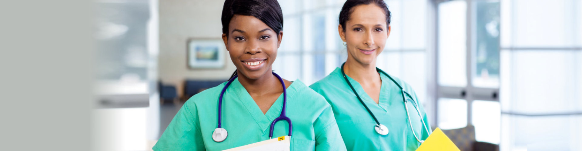 two female nurse wearing stethoscopes smiling