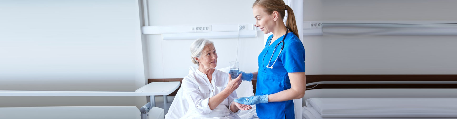 female nurse giving medication and a glass of water to senior woman